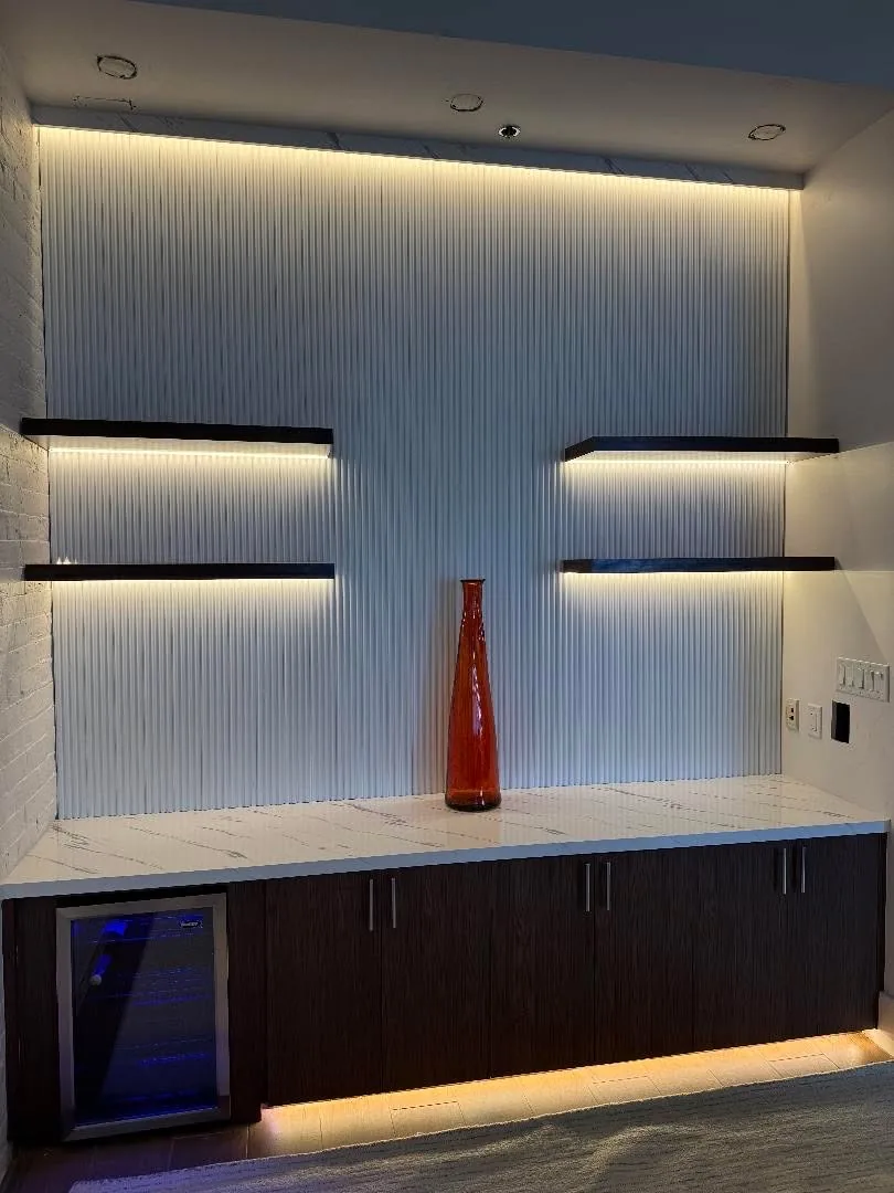 A marble media wall with lit niches and a linear fireplace